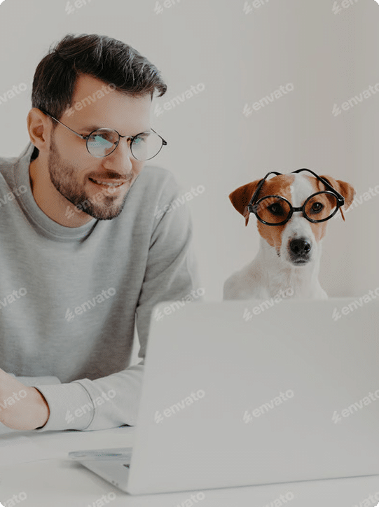 A man and a dog both wearing glasses sit side by side and look at a laptop screen.